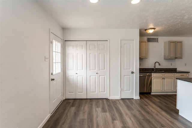 kitchen with stainless steel dishwasher, dark stone countertops, dark hardwood / wood-style floors, and sink