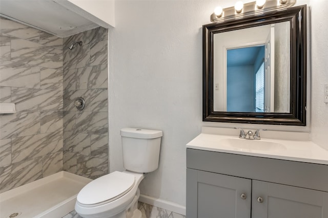 bathroom featuring a tile shower, oversized vanity, and toilet