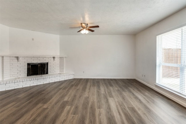 unfurnished living room featuring a textured ceiling, dark hardwood / wood-style flooring, a fireplace, and ceiling fan