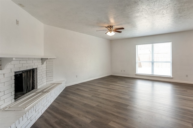 unfurnished living room with a brick fireplace, dark hardwood / wood-style flooring, a textured ceiling, and ceiling fan