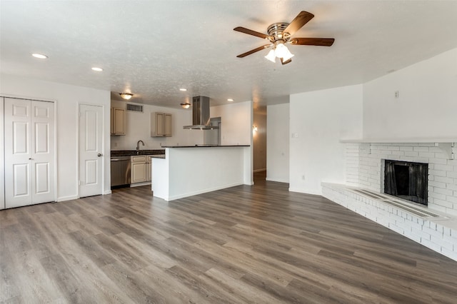 unfurnished living room featuring dark hardwood / wood-style floors, ceiling fan, sink, a brick fireplace, and a textured ceiling