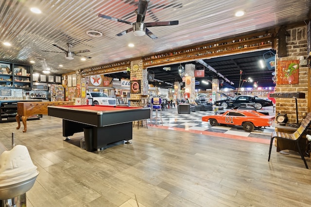 game room with visible vents, a ceiling fan, wood finished floors, pool table, and a bar