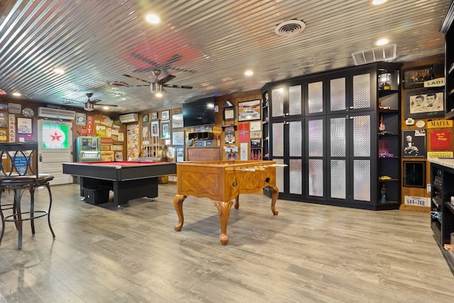 playroom featuring light wood-type flooring, visible vents, and a wall mounted AC