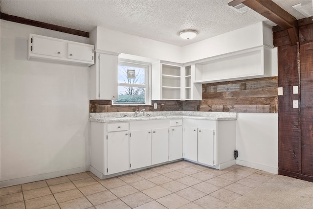 kitchen with white cabinetry, a textured ceiling, light tile flooring, and sink