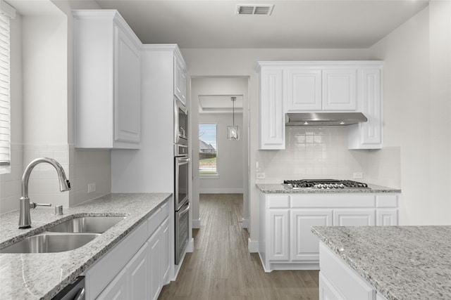 kitchen featuring backsplash, light stone counters, white cabinetry, and light wood-type flooring