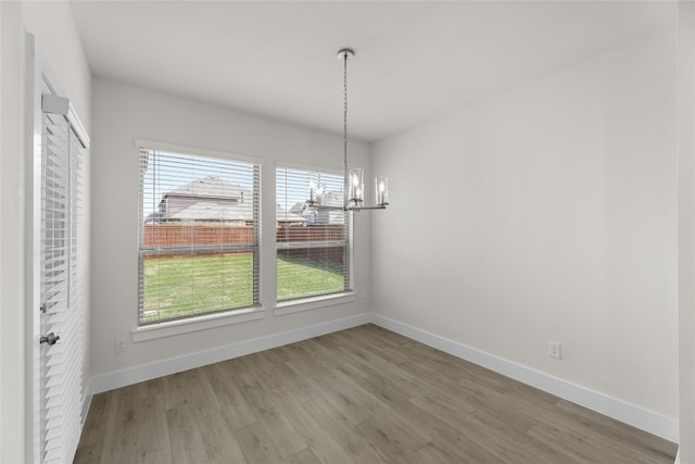 unfurnished room with light wood-type flooring and a chandelier