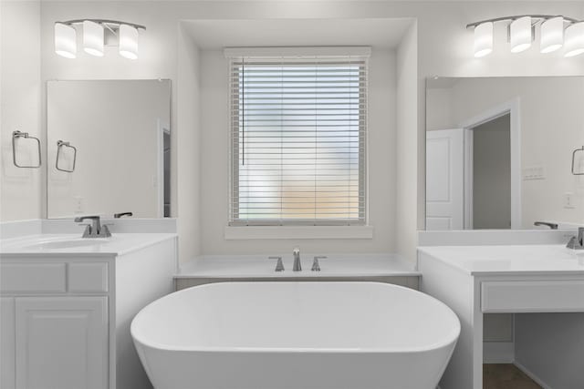 bathroom with oversized vanity, double sink, and a bath to relax in