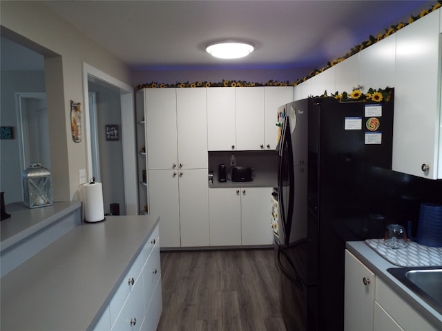 kitchen featuring black refrigerator, dark wood-type flooring, white cabinets, and sink