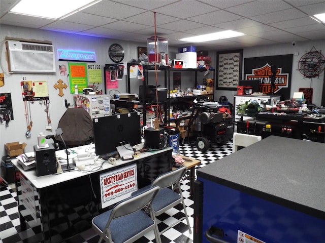 interior space with a drop ceiling, a wall mounted AC, and a kitchen bar