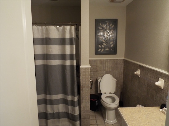 bathroom with tile walls, toilet, and tile flooring