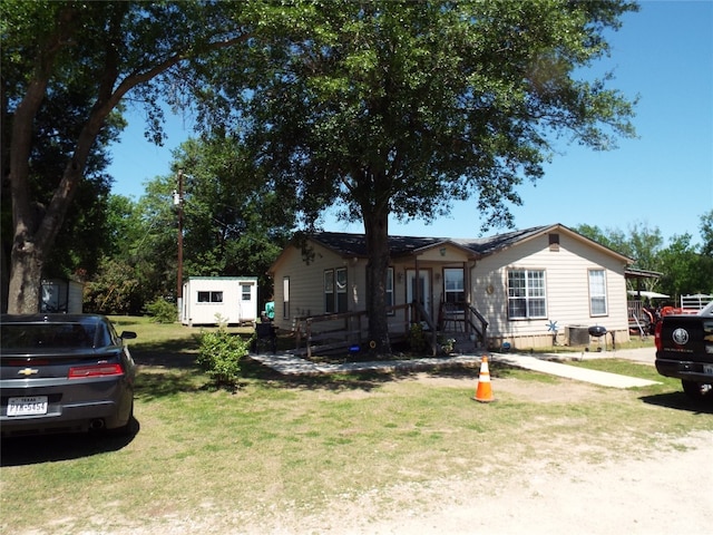 view of front of property with a storage unit and a front yard