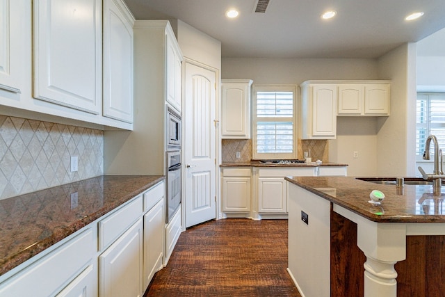 kitchen with sink, dark stone countertops, white cabinets, tasteful backsplash, and dark hardwood / wood-style flooring