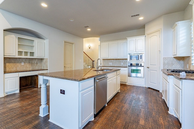 kitchen featuring an island with sink, white cabinetry, backsplash, and appliances with stainless steel finishes