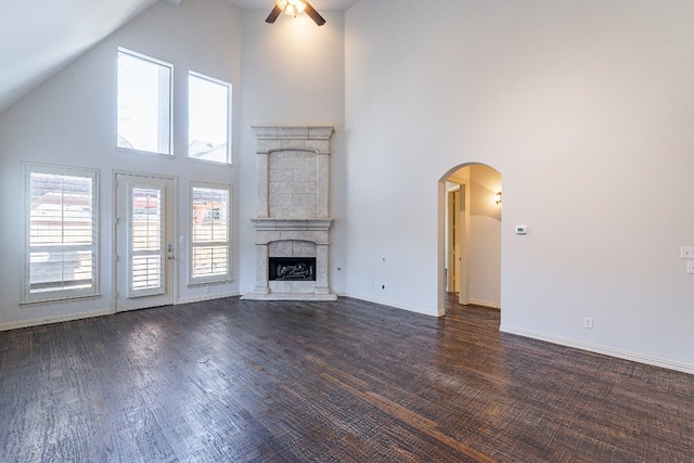 unfurnished living room with ceiling fan, dark wood-type flooring, and high vaulted ceiling