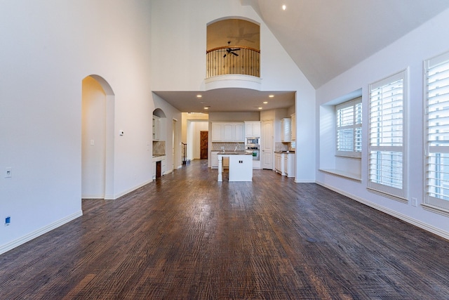 unfurnished living room featuring high vaulted ceiling and dark hardwood / wood-style floors