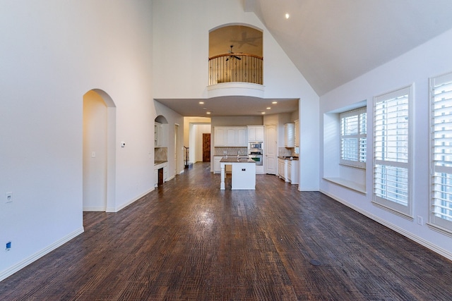 unfurnished living room featuring dark wood-type flooring, high vaulted ceiling, and sink