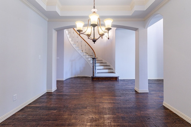 spare room with dark hardwood / wood-style flooring, crown molding, a tray ceiling, and a chandelier