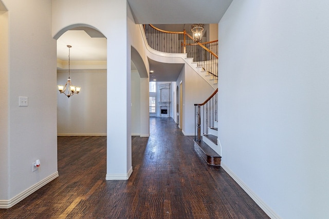 foyer featuring a towering ceiling, ornamental molding, a notable chandelier, and dark hardwood / wood-style floors