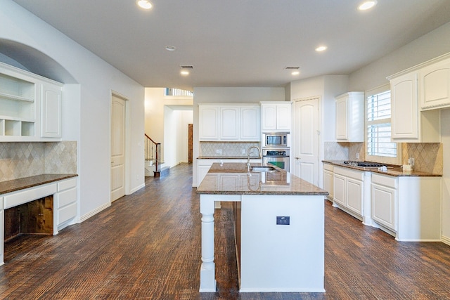 kitchen with appliances with stainless steel finishes, white cabinetry, tasteful backsplash, and dark wood-type flooring