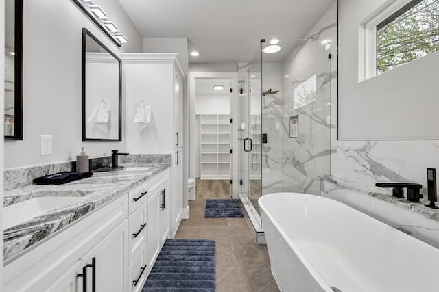 bathroom featuring double sink, plus walk in shower, tile floors, and vanity with extensive cabinet space