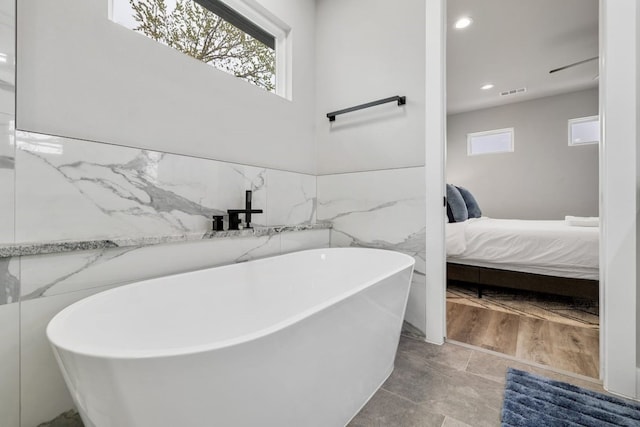 bathroom with a tub, tile walls, and tile floors