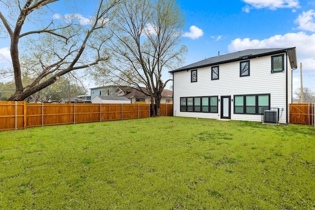 back of property with central AC unit and a yard