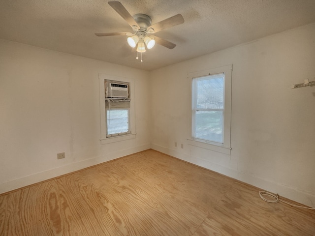 unfurnished room with light hardwood / wood-style flooring, a wealth of natural light, an AC wall unit, and ceiling fan