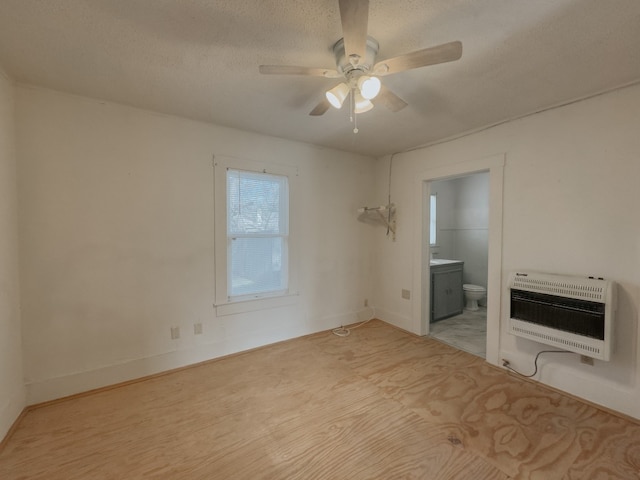 unfurnished bedroom featuring a textured ceiling, ceiling fan, heating unit, and ensuite bath