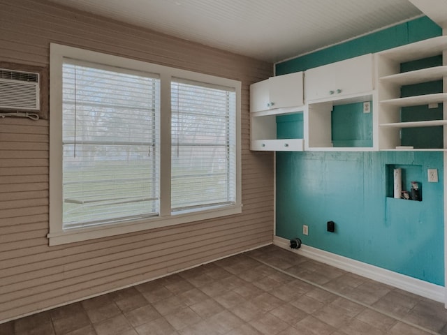 interior space with hookup for a washing machine, wooden walls, a wall mounted AC, and cabinets