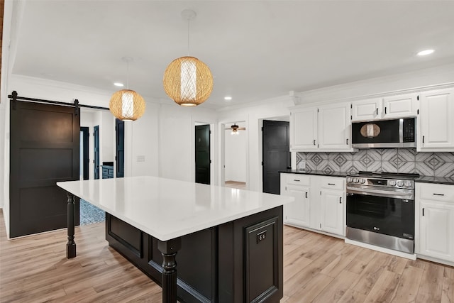 kitchen featuring pendant lighting, light hardwood / wood-style floors, a barn door, tasteful backsplash, and appliances with stainless steel finishes