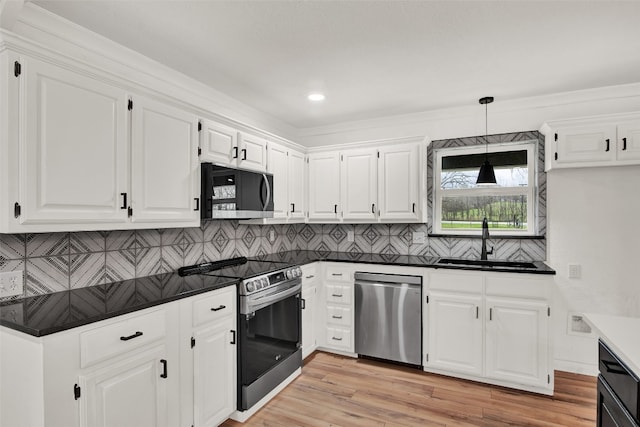 kitchen with sink, hanging light fixtures, appliances with stainless steel finishes, backsplash, and light hardwood / wood-style floors