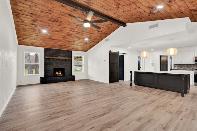 unfurnished living room featuring brick wall, a brick fireplace, ceiling fan, beamed ceiling, and light wood-type flooring