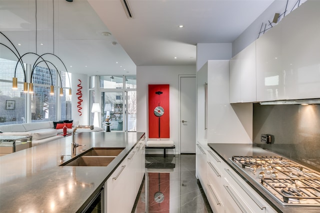 kitchen featuring sink, wine cooler, stainless steel gas stovetop, white cabinets, and dark tile patterned flooring