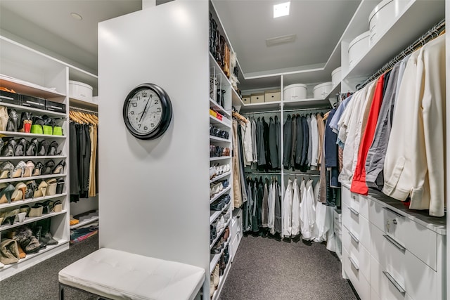 walk in closet with dark carpet