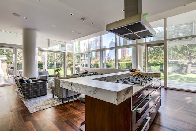 kitchen with a wall of windows, dark wood-type flooring, a center island, and island range hood