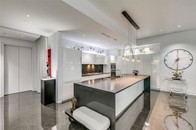 kitchen with white cabinetry, sink, pendant lighting, and a kitchen island