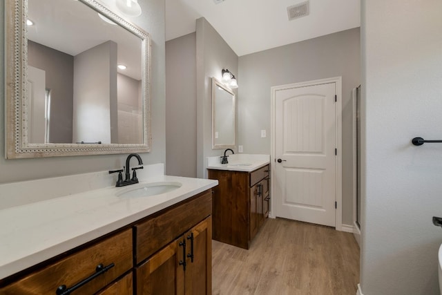 bathroom featuring wood-type flooring, double sink, and vanity with extensive cabinet space