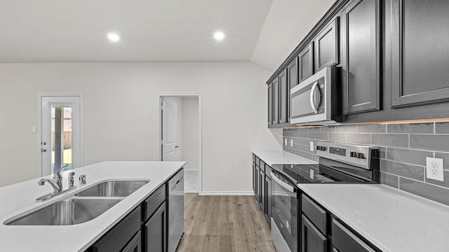 kitchen with sink, lofted ceiling, light hardwood / wood-style flooring, backsplash, and appliances with stainless steel finishes