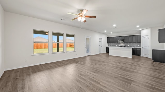 unfurnished living room with ceiling fan and dark wood-type flooring