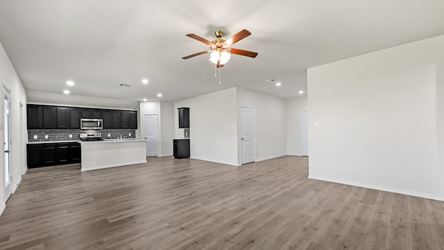 kitchen with ceiling fan, stainless steel appliances, hardwood / wood-style floors, and a center island