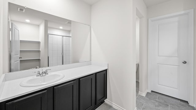 bathroom with tiled shower, vanity, and tile patterned flooring