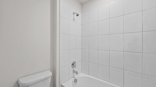 bathroom with tiled shower / bath combo and toilet