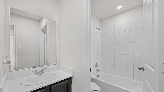 full bathroom with tiled shower / bath, vanity, and toilet