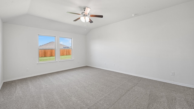 empty room with vaulted ceiling, ceiling fan, and carpet floors