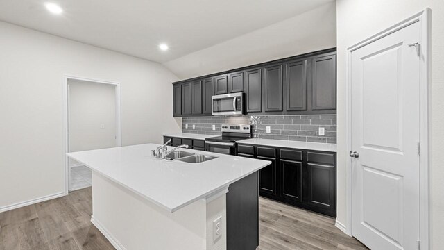 kitchen featuring an island with sink, sink, light hardwood / wood-style flooring, and stainless steel appliances