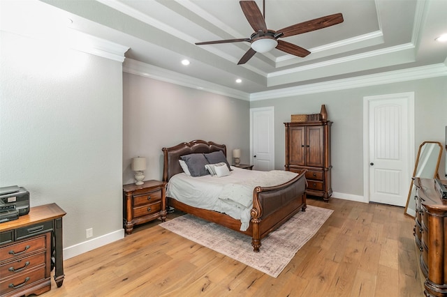 bedroom featuring light wood-type flooring, a tray ceiling, ceiling fan, and ornamental molding