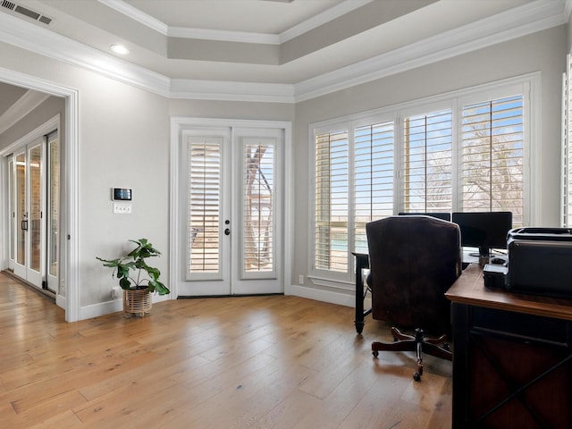 office featuring a tray ceiling, french doors, crown molding, visible vents, and light wood-style floors