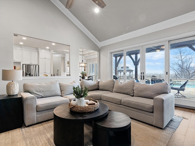 living room with ornamental molding, an inviting chandelier, high vaulted ceiling, and light hardwood / wood-style flooring