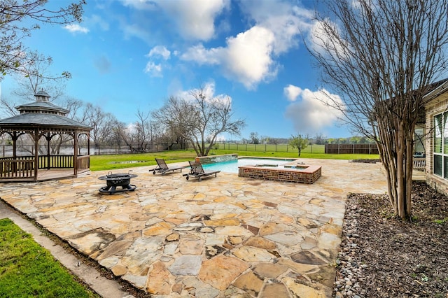 view of patio with a gazebo, a fire pit, and a pool with hot tub