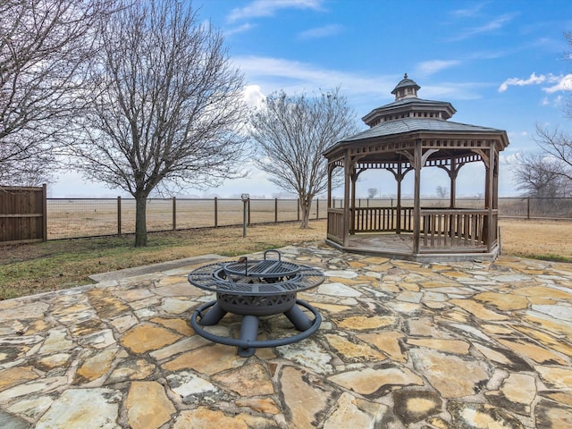 view of patio / terrace featuring an outdoor fire pit, a rural view, fence, and a gazebo